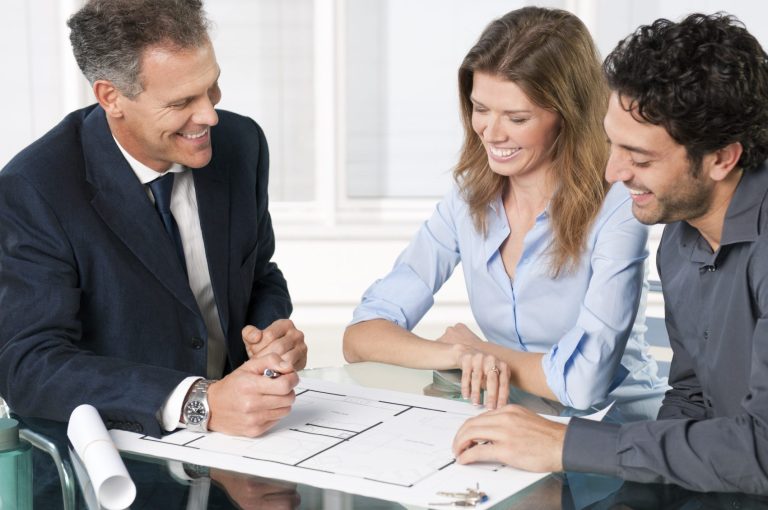 Three people at a desk looking at a document